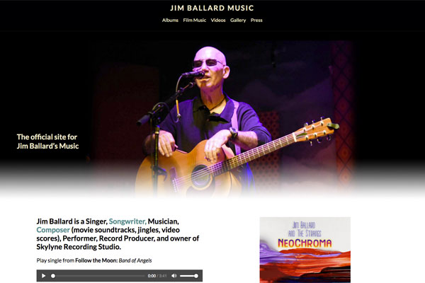 JimBallardMusic.net homepage - Jim holding guitar, at microphone, with multi-colored lights shining on him.